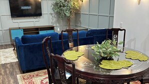 A dining area with a round table, chairs, and a blue sofa in the background. - Cozy bed & breakfast in charming Ypsilanti with AC, WiFi (Ypsilanti)