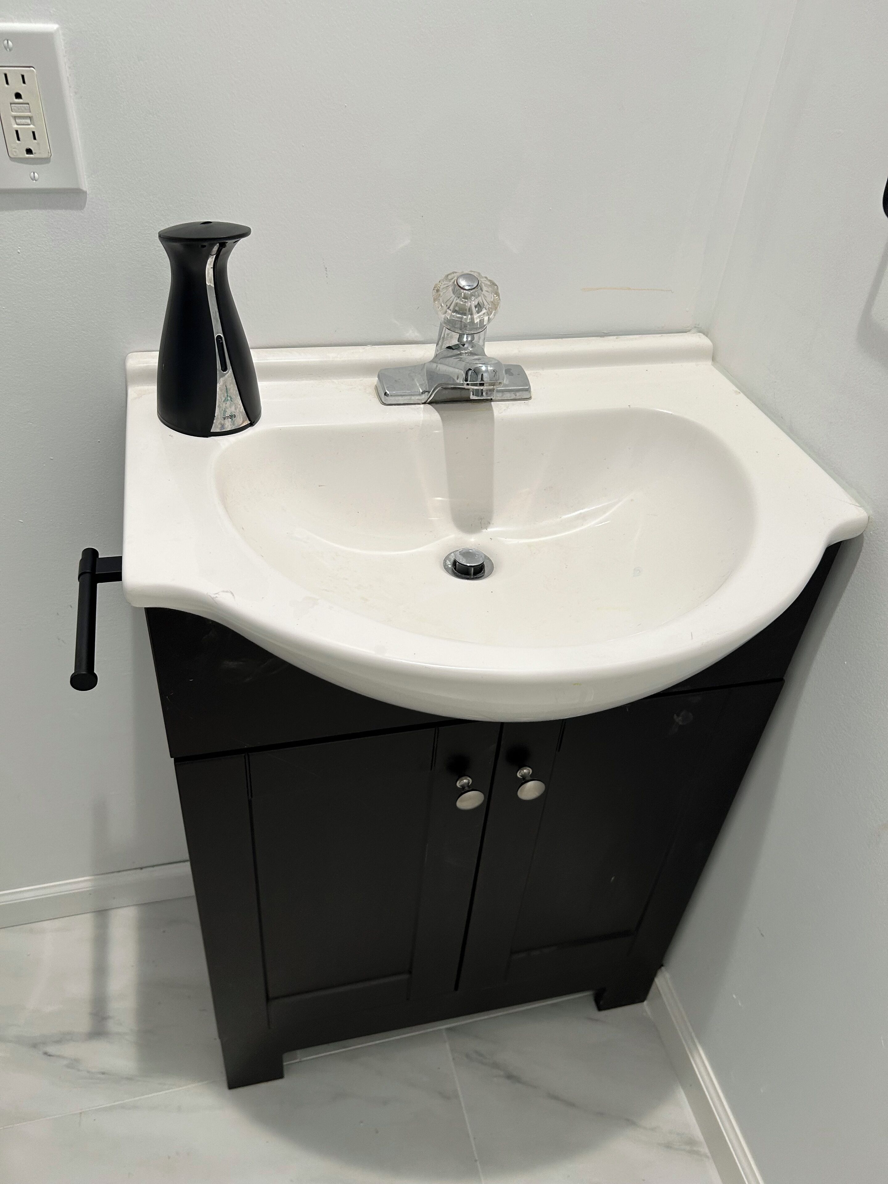 Une salle de bain avec un lavabo blanc, un meuble noir et un robinet noir.
