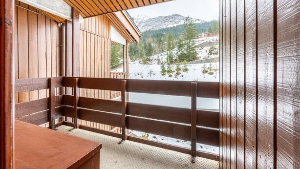 Un balcón de madera con vistas a un paisaje montañoso nevado.