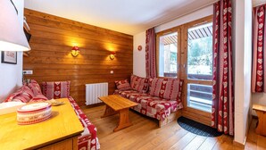 Una habitación acogedora con pared de madera, un sofá, una mesa y una ventana con cortinas.