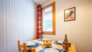 Una mesa de comedor dispuesta con platos, un frutero, una botella de vino y una copa.