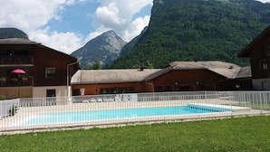 Ein Poolbereich mit einem Holzbauten, einem weißen Zaun und einem Berg im Hintergrund.