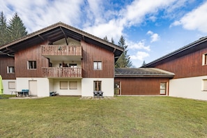 Un chalet en bois doté d’un balcon, d’une terrasse couverte et d’une cour gazonnée.