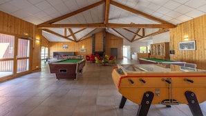 Ein großzügiger, überdachter Erholungsbereich mit Holzwänden, einer Billardkugel, einem Tischfußballtisch und einem Snookertisch.
