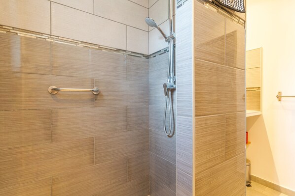 Een douche met een handdouche en een kraan op de muur.