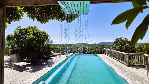 Une piscine dotée d’une terrasse en bois, de chaises longues et offrant une vue sur le paysage.