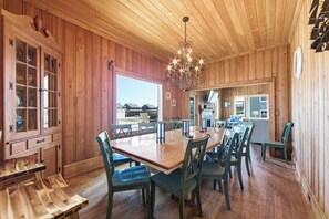 A wooden interior with a dining area, wooden cabinets, and a chandelier. - Resting Beach Face: Semi-Oceanfront, Classic Nags Head Flat Top Home, Private Pool, Hot Tub (Nags Head)