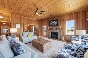 Ein Holzinterieur mit Kamin, Fernseher und Blick ins Freie.