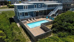 Une maison à deux étages avec une piscine, des chaises longues et un escalier.