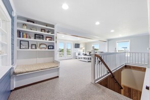 A spacious room with a built-in bench, a staircase, and a view of the outdoors. - Resting Beach Face: Semi-Oceanfront, Classic Nags Head Flat Top Home, Private Pool, Hot Tub (Nags Head)