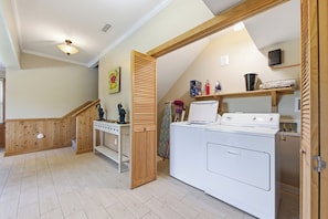 Un espace buanderie comprenant un lave-linge, un étendoir et un escalier en bois.