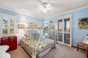A child's bedroom with bunk beds, a desk, and a window with blinds.