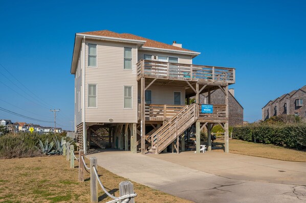A two-story house with a wooden deck and stairs leading to a balcony.