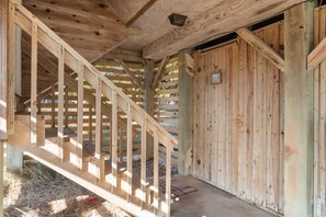 Un escalier en bois mène à une zone abritée, dotée d’une porte en métal et d’une petite fenêtre.