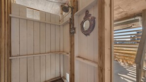 Une cabane en bois avec une douche, un miroir et une fenêtre.
