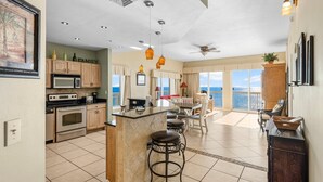 A spacious kitchen with a central island, a dining area with a view, and a balcony overlooking the ocean.