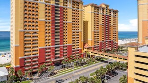 A multi-story hotel with balconies, a beach view, and a parking area.