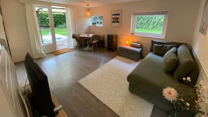 A cozy living room with a sofa, a TV, a dining table, and a fireplace.
