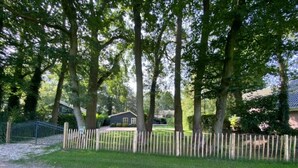 A fenced yard with trees and a house in the background.