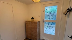 A hallway with a wooden cabinet, a gray rug, and a door with a window.