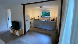 A compact kitchen with a washing machine, a sink, and a window with a view of greenery.