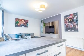 Una sala de estar moderna con comedor, televisor de pantalla plana y obras de arte en las paredes.