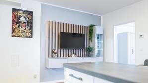 Una cocina moderna con televisor integrado, pared de paneles de madera y una planta en maceta.