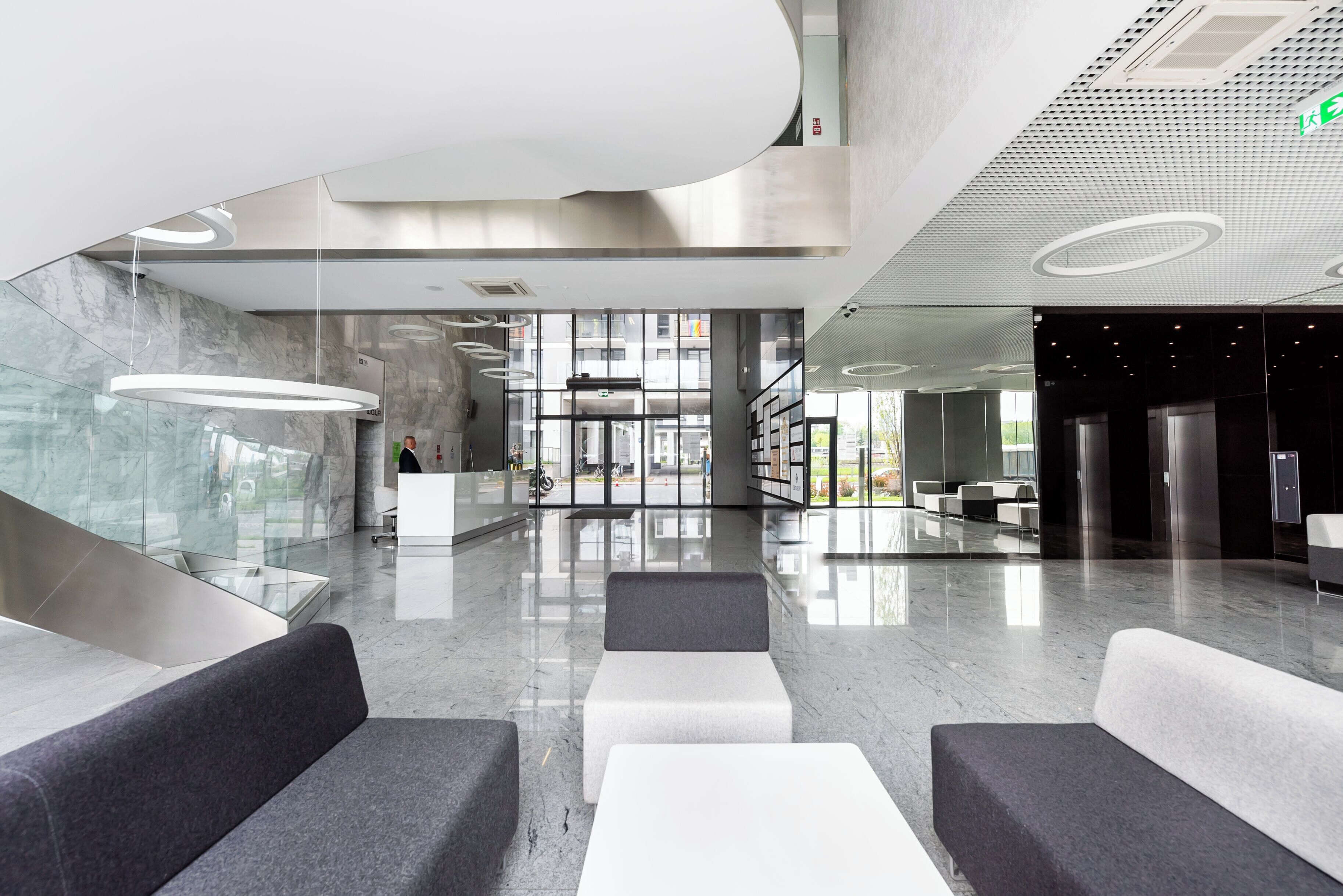 A modern lobby with a glass wall, seating areas, and a reception desk.