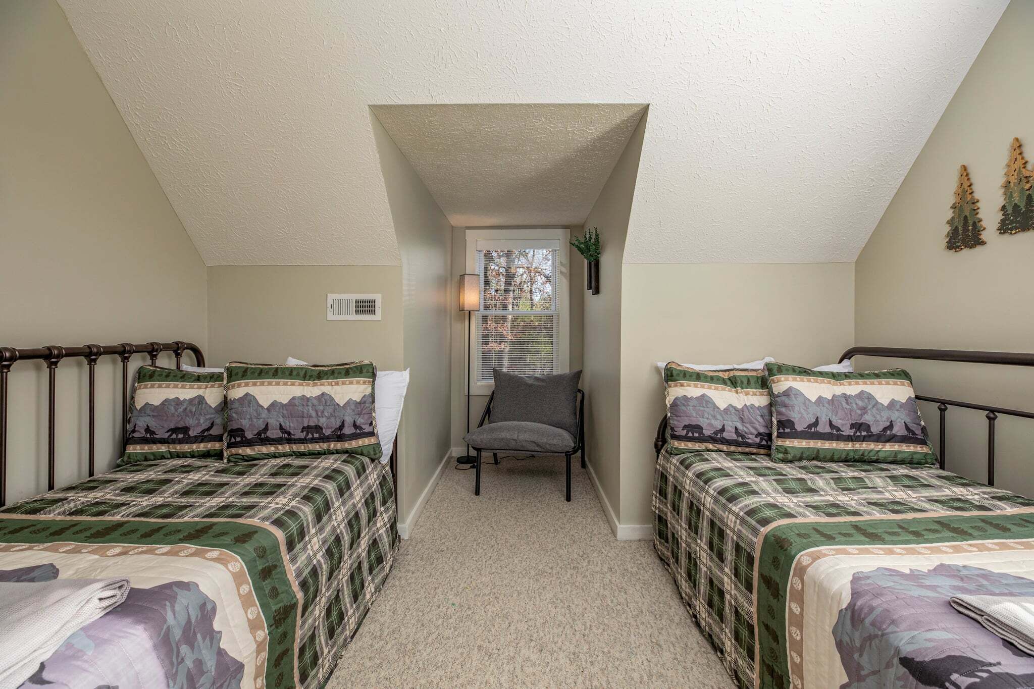 A bedroom with two beds, a chair, and a window with blinds.