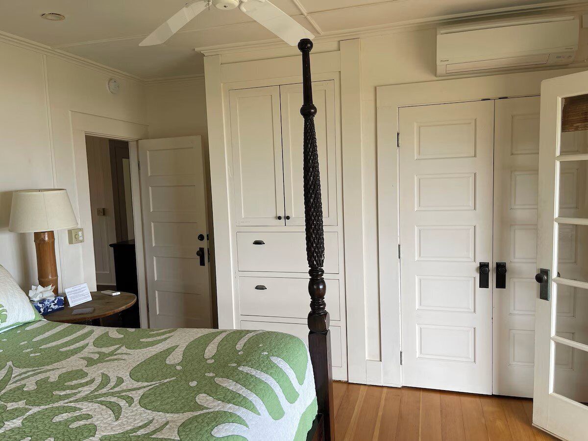 Un dormitorio con cama con dosel, puertas blancas y ventilador de techo.