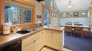 A kitchen with wooden cabinets, a dishwasher, and a sink. There is a dining area with a table and chairs.
