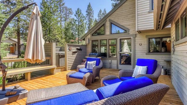A wooden deck with wicker furniture and a grill area.