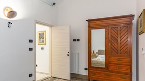 Ett hotellrum med en garderob i trä, en dörr som leder till ett annat rum, ett element och en inramad tavla på väggen.