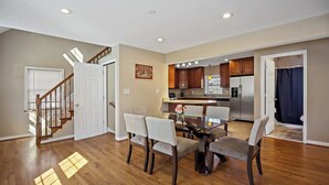 A spacious living area with a dining table, chairs, and a kitchen in the background. - Fresh | 4 bedroom | Luxury | Center | Sunny (Falls Church)