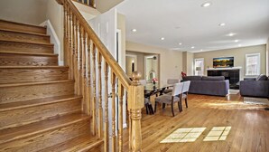 A spacious living area with a wooden staircase, a fireplace, and a dining area. - Fresh | 4 bedroom | Luxury | Center | Sunny (Falls Church)