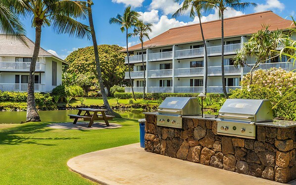 A hotel with a pool, outdoor grills, and a well-maintained lawn.