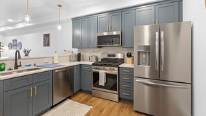 Una cucina moderna con mobili grigi, elettrodomestici in acciaio inossidabile e luci a sospensione.