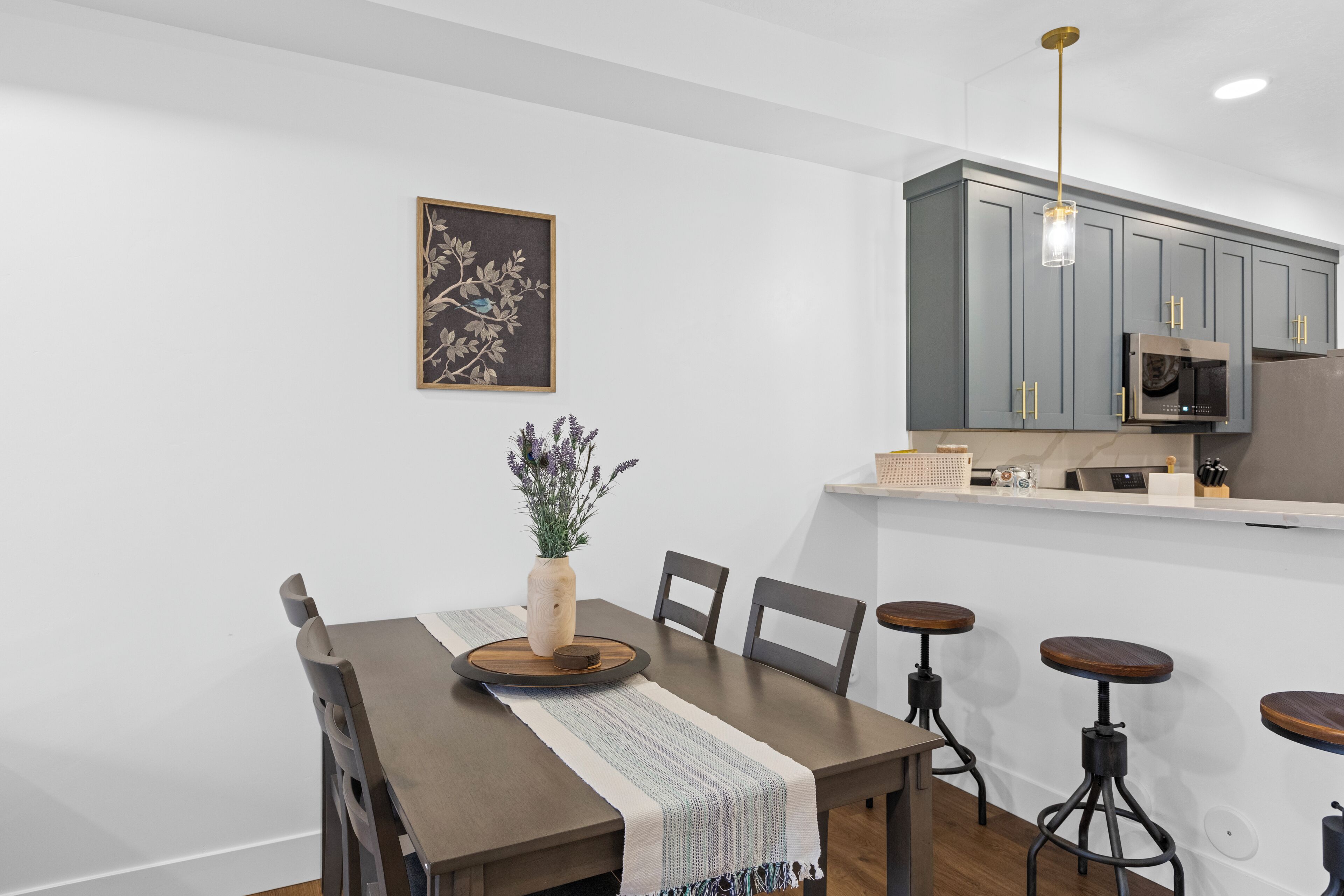 A modern dining area with a wooden table, chairs, and a vase of flowers.