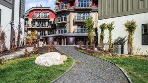 A multi-story building with balconies, a gravel pathway, and a landscaped garden. - Luxury in Downtown McCall, Walking Distance to Everything Downtown (McCall)