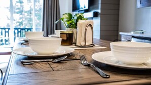 A dining table set with white bowls, plates, and cutlery, a plant, a jar, and a napkin holder. - Luxury in Downtown McCall, Walking Distance to Everything Downtown (McCall)