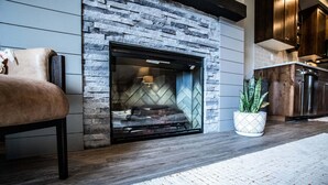 A modern living room with a stone fireplace, a leather sofa, and a potted plant. - Luxury in Downtown McCall, Walking Distance to Everything Downtown (McCall)