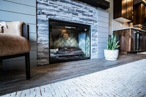 A modern living room with a stone fireplace, a leather sofa, and a potted plant. - Luxury in Downtown McCall, Walking Distance to Everything Downtown (McCall)