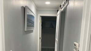 A hallway with a patterned carpet, a framed picture on the wall, and a door leading to another room. - Charming 2-bedroom house with dock, AC, & Wifi. Enjoy kayaking
2 min from beach (Vero Beach)