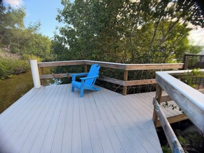A wooden deck with a blue chair and a wooden railing overlooking a body of water.