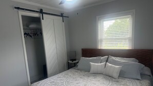 A bedroom with a bed, a wardrobe, a nightstand, and a window with blinds. - Charming 2-bedroom house with dock, AC, & Wifi. Enjoy kayaking
2 min from beach (Vero Beach)