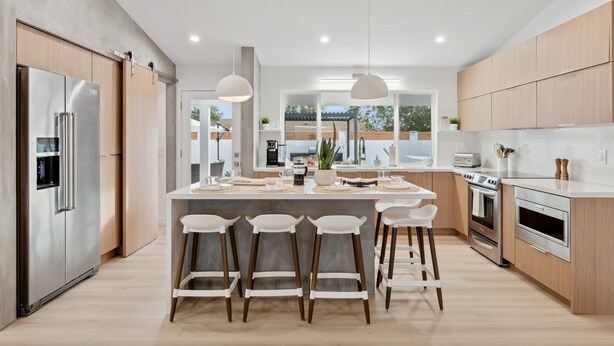 Een moderne keuken met een centraal eiland, roestvrijstalen apparatuur, houten kastjes en een groot raam met uitzicht.