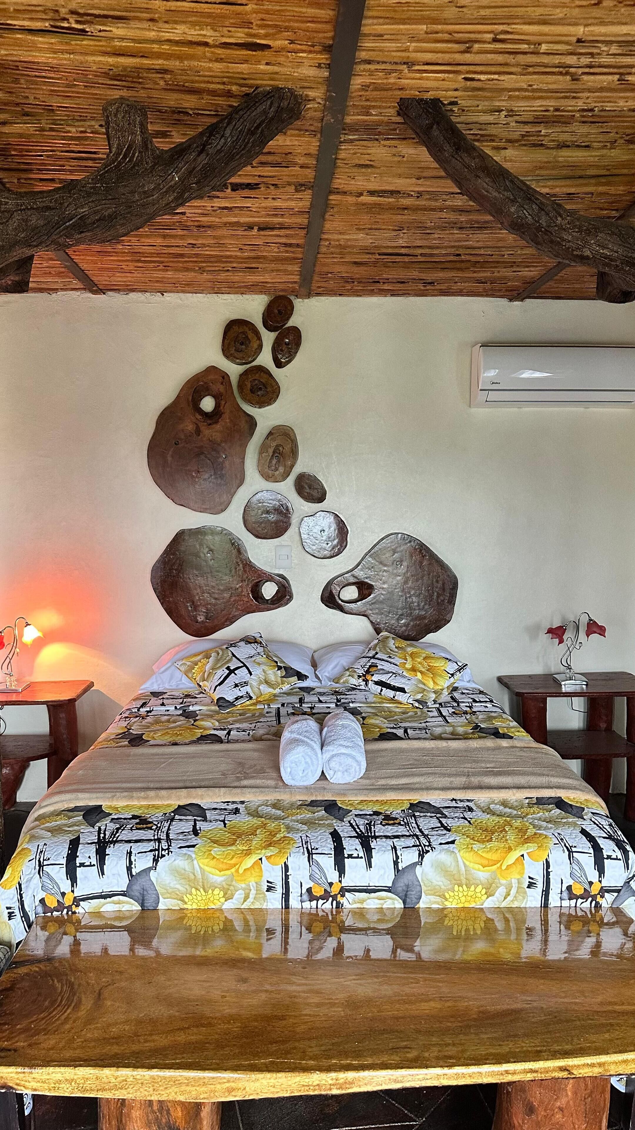 Ein Zimmer mit einem Bett, einer Holzbalkendecke und einer Wand mit dekorativer Steinmalerei.