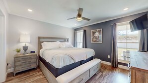 Een slaapkamer met een bed, nachtkastje, lamp en uitzicht op het omliggende landschap.