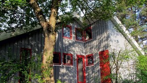 Eine rustikale Holzhütte mit geneigtem Dach, umgeben von Bäumen.