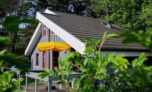 Ein Haus mit geneigtem Dach, einer Veranda mit gelbem Markisenstoff und einer Garage.